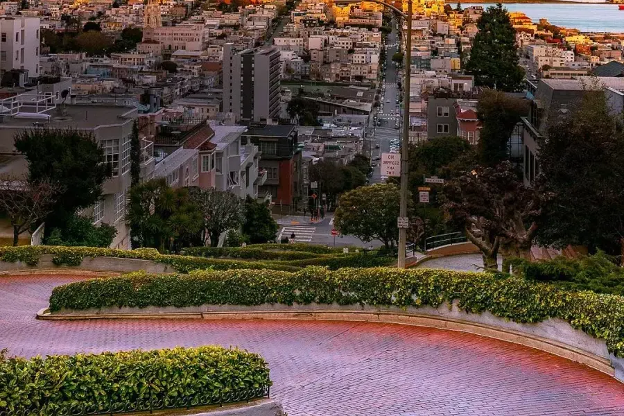 lombard street curves with Coit Tower in the distance during sunset.